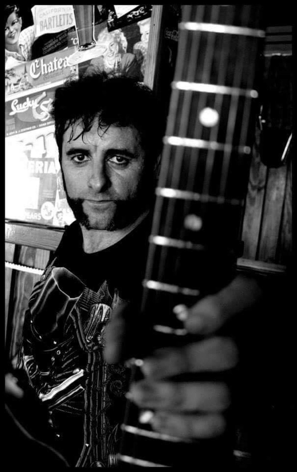 Retrato de Kike tras el mástil de su guitarra